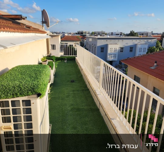 מעקה לבן לאורך מרפסת עם דשא סינתטי